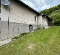 Predaj domu v Janovej Lehote - Rodinný dom v Janovej Lehote obklopený záhradou, so satelitnou anténou na fasáde.