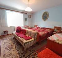 Predaj domu v Janovej Lehote - Izba v rodinnom dome s posteľou, sedačkou a dekoratívnym kobercom.