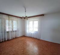 : Predaj rodinného domu s veľkým pozemkom v obci Pitelová  - Svetlá izba s bielymi závesmi a podlahou s dreveným dekorom v rodinnom dome.