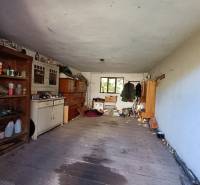 : Predaj rodinného domu s veľkým pozemkom v obci Pitelová  - Pivnica v rodinnom dome s policami, starým nábytkom a rôznymi predmetmi.