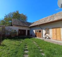 : Predaj rodinného domu s veľkým pozemkom v obci Pitelová  - Rodinný dom v Pitelovej s drevenou strechou a zelenou záhradou.