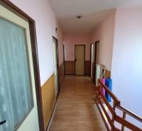 : Predaj rodinného domu s veľkým pozemkom v obci Pitelová  - Chodba v rodinnom dome s podlahou s dreveným dekorom a dreveným zábradlím.