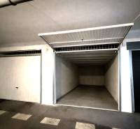 REZERVOVANÉ-PREDAJ 2 izbový byt s garážou v skvelej lokalite v Ružinov - Otvorená garáž s prázdnym interiérom a bielymi stenami.