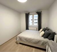 REZERVOVANÉ-PREDAJ 2 izbový byt s garážou v skvelej lokalite v Ružinov - Spálňa s posteľou a podlahou s dreveným dekorom v 2-izbovom byte.