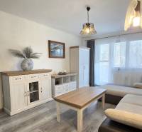 Moderný 2-izbový byt po rekonštrukcii v srdci Zlatého potoka - Zvolen - Obývacia izba v 2-izbovom byte s podlahou s dreveným dekorom, sedačkou a bielym nábytkom.