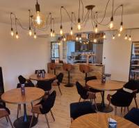 Prenájom kaviarne  v obci Nová Dedinka pri Senci - Interiér gastro priestorov s podlahou s dreveným dekorom a osvetlením žiarovkami.