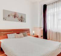  VÝNIMOČNÝ 4-izbový byt rozdelený na DVA SAMOSTATNÉ BYTY - Spálňa v 4-izbovom byte s podlahou s dreveným dekorom a obrazom orchideí.