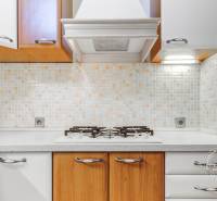  VÝNIMOČNÝ 4-izbový byt rozdelený na DVA SAMOSTATNÉ BYTY - Kuchyňa v 4-izbovom byte s bielymi a drevenými skrinkami a mozaikovými obkladmi.