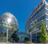  VÝNIMOČNÝ 4-izbový byt rozdelený na DVA SAMOSTATNÉ BYTY - Budovy s presklenou fasádou na rušnej ulici, jasné nebo, slnečný deň.