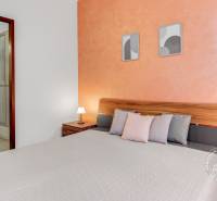  VÝNIMOČNÝ 4-izbový byt rozdelený na DVA SAMOSTATNÉ BYTY - Spálňa s dvojlôžkom, nočnými stolíkmi a oranžovou stenou v 4-izbovom byte.