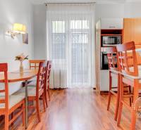  VÝNIMOČNÝ 4-izbový byt rozdelený na DVA SAMOSTATNÉ BYTY - Jasná kuchyňa so stolom a stoličkami v 4-izbovom byte s podlahou s dreveným dekorom.