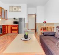  VÝNIMOČNÝ 4-izbový byt rozdelený na DVA SAMOSTATNÉ BYTY - Kuchyňa v 4-izbovom byte so sedačkou, kvetmi a podlahou s dreveným dekorom.