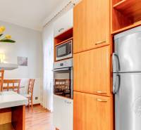  VÝNIMOČNÝ 4-izbový byt rozdelený na DVA SAMOSTATNÉ BYTY - Kuchyňa v 4-izbovom byte s mikrovlnkou, chladničkou, kvetinovou výzdobou a podlahou s dreveným dekorom.