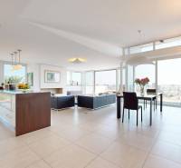 Exkluzívny byt pod Slavínom s terasou a výhľadom na Bratislavu - Priestranná obývačka s presklenou stenou, modernou kuchyňou a výhľadom v 4-izbovom byte.