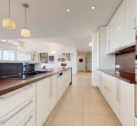 Exkluzívny byt pod Slavínom s terasou a výhľadom na Bratislavu - Kuchyňa v 4-izbovom byte s bielymi skrinkami a podlahou v drevenom dekore.