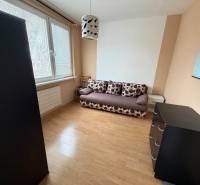 3 izbový byt bez balkóna Topoľčany  - Izba s pohovkou, komodou a podlahou s dreveným dekorom v 3-izbovom byte.