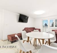 NADŠTANDARDNÁ REKREAČNÁ CHATA | DUCHONKA  - Obývačka chaty s bielym jedálenským stolom, pohovkami a televízorom na stene.