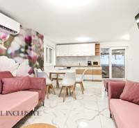 NADŠTANDARDNÁ REKREAČNÁ CHATA | DUCHONKA  - Chata interiér s kvetinovou tapetou, kuchyňou, ružovými sedačkami a jedálenskými stoličkami.