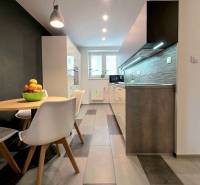 KH-1056, Moderný 2 izbový tehlový byt, Jilemnického, Košice - Kuchyňa v 2-izbovom byte s jedálenským stolom, dlažbou a svetlami nad pracovnou doskou.