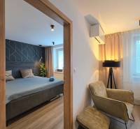 KH-1056, Moderný 2 izbový tehlový byt, Jilemnického, Košice - Dvojizbový byt s podlahou s dreveným dekorom zahŕňa spálňu, kreslo a lampu.