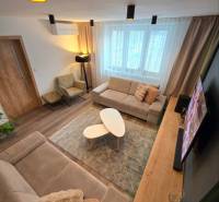 KH-1056, Moderný 2 izbový tehlový byt, Jilemnického, Košice - Obývačka v 2-izbovom byte s pohodlnou pohovkou, konferenčnými stolíkmi a podlahou s dreveným dekorom.