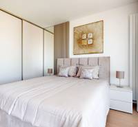 RIVERS | Butikovo zariadený ateliér na 32. poschodí Eurovea Tower - Spálňa v 2-izbovom byte s posteľou, vstavanou skriňou a podlahou s dreveným dekorom.