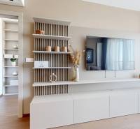 RIVERS | Butikovo zariadený ateliér na 32. poschodí Eurovea Tower - Obývacia časť s televízorom, policami a podlahou s dreveným dekorom v 2-izbovom byte.