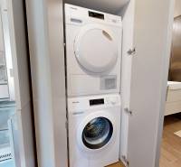 RIVERS | Butikovo zariadený ateliér na 32. poschodí Eurovea Tower - Kompaktná práčka a sušička v bielej skrinke v 2-izbovom byte.