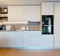 RIVERS | Butikovo zariadený ateliér na 32. poschodí Eurovea Tower - Kuchyňa v 2-izbovom byte s bielymi skrinkami a podlahou s dreveným dekorom.