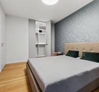 ︱ PREDAJ Nadštandardný 3-izb. byt v projekte Gansberg Koliba - Spálňa s vstavanou skriňou, čalúnenou posteľou a podlahou s dreveným dekorom v 3-izbovom byte.