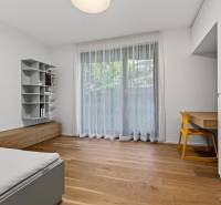 ︱ PREDAJ Nadštandardný 3-izb. byt v projekte Gansberg Koliba - Izba s podlahou s dreveným dekorom, stolík so žltou stoličkou, posteľ, polička.