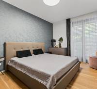 ︱ PREDAJ Nadštandardný 3-izb. byt v projekte Gansberg Koliba - Spálňa s dvojposteľou, tapetou a podlahou s dreveným dekorom v 3-izbovom byte.