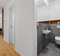 ︱ PREDAJ Nadštandardný 3-izb. byt v projekte Gansberg Koliba - V 3-izbovom byte sa nachádza toaleta s sivými obkladmi a podlaha s dreveným dekorom.