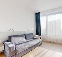 Elegantný byt na mieru s panorámou hradu  - Obývacia izba v 3-izbovom byte s pohovkou, pracovným stolom a podlahou s dreveným dekorom.