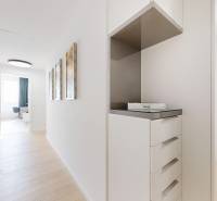 Elegantný byt na mieru s panorámou hradu  - Svetlá chodba s podlahou s dreveným dekorom a bielym nábytkom v 3-izbovom byte.