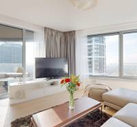 Elegantný byt na mieru s panorámou hradu  - Obývacia izba v 3-izbovom byte so sedačkou, televíziou a podlahou s dreveným dekorom.