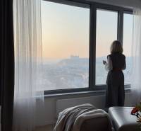 Elegantný byt na mieru s panorámou hradu  - Žena pozorujúca výhľad z 3-izbového bytu s kvetmi a podlahou s dreveným dekorom.