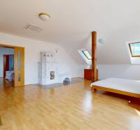 RIVERS - Veľkorysý rodinný dom po rekonštrukcii  - Podkrovná izba v rodinnom dome s kachľovou pecou a podlahou s dreveným dekorom.