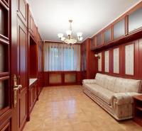 Veľkometrážny byt na Slavíne s výhľadom na mesto - Interiér obývačky s dreveným nábytkom, pohovkou a elegantným lustrom, poskytujúci pohodlie.