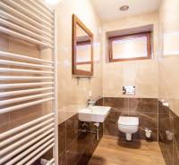 Nadštandardný 4-izbový rodinný dom s garážou a veľkým pozemkom - Kúpeľňa v rodinnom dome s podlahou s dreveným dekorom, umývadlom a vykurovacím telesom.