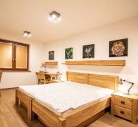 Nadštandardný 4-izbový rodinný dom s garážou a veľkým pozemkom - Spálňa v rodinnom dome s podlahou s dreveným dekorom, obrazmi a pracovnými stolmi.