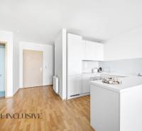 Na predaj luxusný 2-izb. byt s loggiou v Bratislave  - Kuchyňa v 2-izbovom byte s bielymi skrinkami a podlahou s dreveným dekorom.