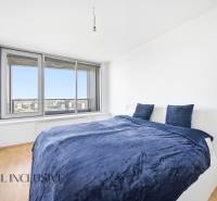 Na predaj luxusný 2-izb. byt s loggiou v Bratislave  - Spálňa v 2-izbovom byte s posteľou a veľkým oknom, podlaha s dreveným dekorom.