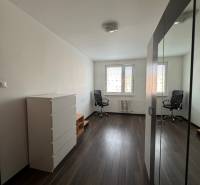 Prenájom 2-izb bytu v Bratislave-Rača - Svetlá izba s podlahou s dreveným dekorom, skriňou a kreslom v 2-izbovom byte.