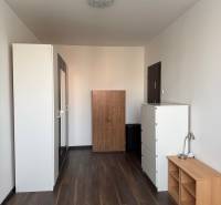 Prenájom 2-izb bytu v Bratislave-Rača - Miestnosť v 2-izbovom byte s podlahou s dreveným dekorom, bielymi skriňami a nábytkom.