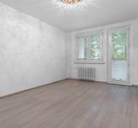 I Predaj 3- izbového bytu v Dúbravke - Izba v 3-izbovom byte s podlahou s dreveným dekorom a veľkými oknami.