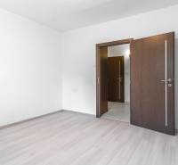 I Predaj 3- izbového bytu v Dúbravke - Izba s podlahou s dreveným dekorom a otvorenými dverami v 3-izbovom byte.