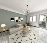 I Predaj 3- izbového bytu v Dúbravke - Obývačka v 3-izbovom byte s pohovkou, stolíkom a umeleckými obrazmi na stene.