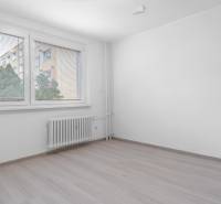 I Predaj 3- izbového bytu v Dúbravke - Prázdna izba s podlahou s dreveným dekorom a oknom v 3-izbovom byte.