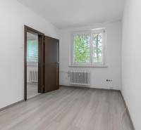 I Predaj 3- izbového bytu v Dúbravke - Prázdna izba s podlahou s dreveným dekorom v 3-izbovom byte, výhľad na zelené stromy.